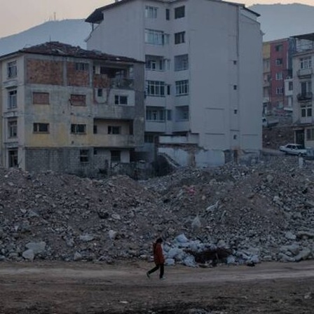 Ein Mädchen geht in der türkischen Stadt Hatay an Schutt und zerstörten Häusern entlang