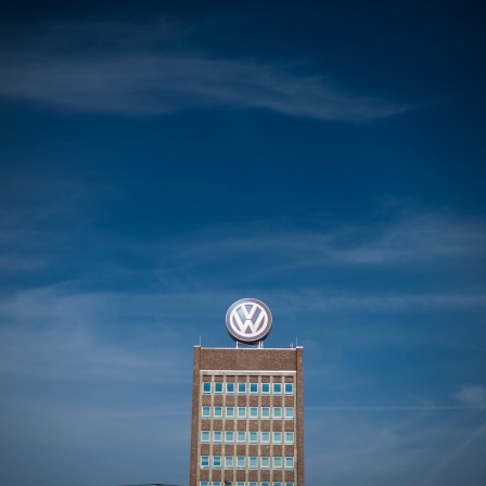 Blauer Himmel über dem Verwaltungshochhaus am Volkswagen-Werk in Wolfsburg, auf dem ein großes VW-Logo angebracht ist.