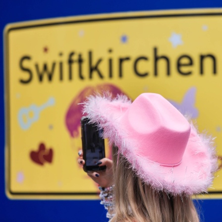 Ein Fan fotografiert vor dem ersten Deutschland-Konzert der Sängerin Taylor Swift in der Gelsenkirchener Innenstadt ein Schild mit der Aufschrift &#034;Swiftkirchen&#034;