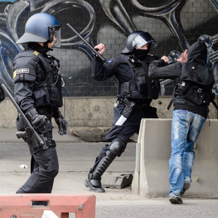 Ein Polizeibeamter setzt nach dem Ende eines rechten Aufmarsches gegen einen linken Gegendemonstranten seinen Schlagstock ein. 
