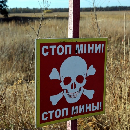 Ein Warnschild "Stop! Minen" ist in dem Bereich zu sehen, in dem die Entminung mit Hilfe modernster Technik durchgeführt wurde in der Region Charkiw (Ukraine).