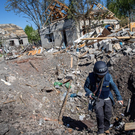 Ein Journalist steigt aus dem Krater einer Raketenexplosion in Slatyne in der Ukraine. 