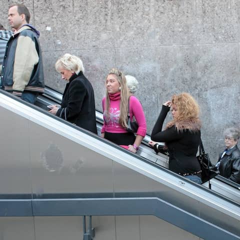 Menschen stehen und warten auf einer Rolltreppe am Stachus in München.