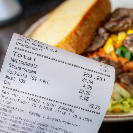 Eine Rechnung der Mehrwertsteuer neben eine vollen Teller in einem Restaurants.