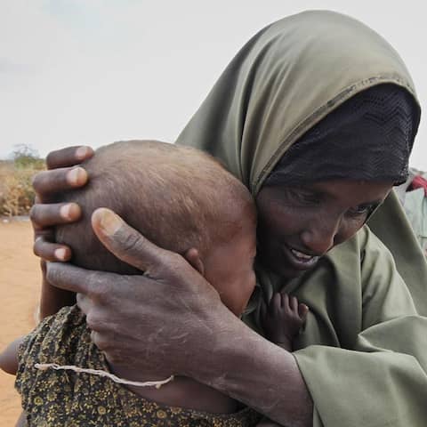 Ein Frau trägt in Kenia ihr kleines Kind auf dem Arm