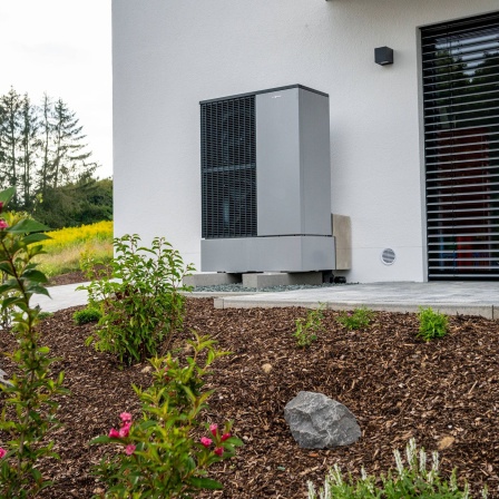 Moderne Wärmepumpe an der Außenwand eines Wohnhauses