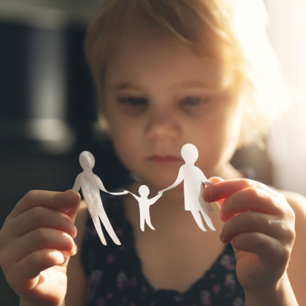 Kleines Mädchen hält einer Familie aus Papier in den Händen