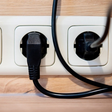 Die Netzstecker mehrerer Küchengeräte stecken in einer Steckdose an einer Küchenzeile.