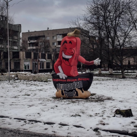 Ein Werbeaufsteller in Form einer roten Paprika mit der Aufschrift "Hungarian Food" steht auf einem leeren Platz.