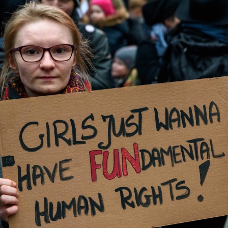 Frau hält Pappschild mit der Aufschrift: &#034;Girls just wanna have FUNdamental Human Rights!&#034;: Solidaritäts-Kundgebung 2018 an der Warschauer Brücke in Berlin gegen die Verschärfung der Gesetze in Polen bei Schwangerschaftsabbrüchen