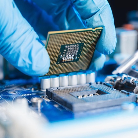 Halbleiter-Produktion: Nahaufnahme einer Hand, die eine CPU (Central processing unit) einsetzt.