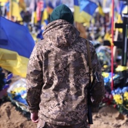 Ein Ukrainischer Soldat steht auf einem Friedhof in Kharkiw vor den Gräbern im Krieg gefallener Ukrainischer Soldaten .