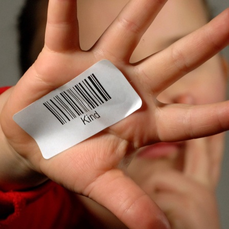 Kleines Mädchen streckt ihre mit einem Barcode beklebte Hand aus