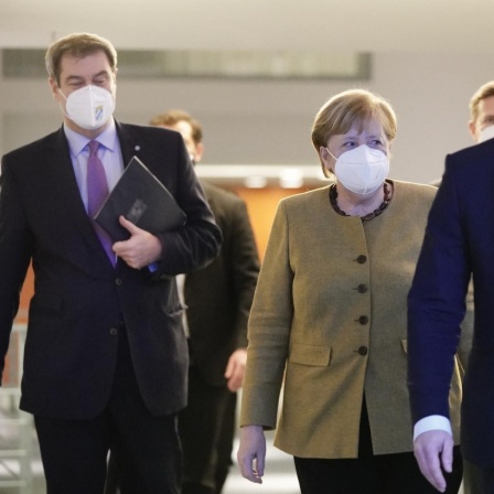 Bundeskanzlerin Angela Merkel (CDU), kommt neben Markus Söder (CSU, l), Ministerpräsident von Bayern und CSU-Vorsitzender, sowie Michael Müller (SPD, r), Regierender Bürgermeister von Berlin, zur Pressekonferenz nach den Beratungen von Bund und Lände