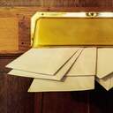 Briefumschläge stecken in einem goldenen Briefkasten