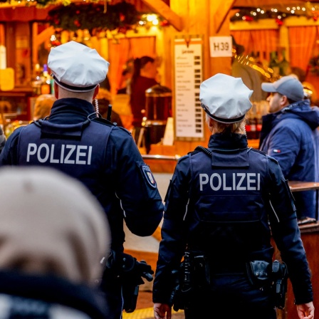 Polizisten gehen über den Weihnachtsmarkt in der Kieler Innenstadt.