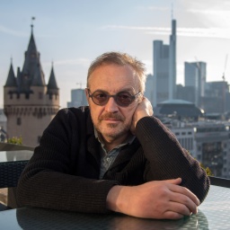 Josef Hader Kabarettist sitzt an einem Tisch und stützt seinen Kopf mit der linken Hand