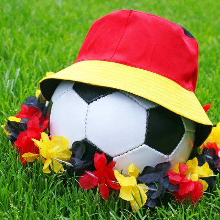 Symbolbild: Ein Fußball mit Hut und Blumenkette in den deutschen Nationalfarben.