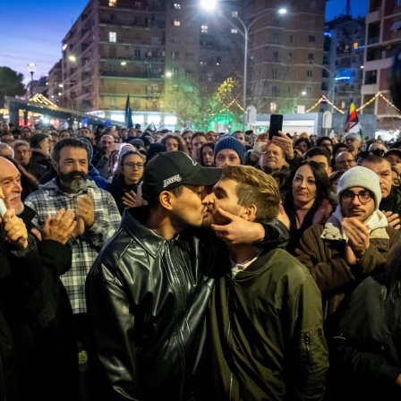 Zwei junge Männer küssen sich bei einer Demonstration gegen Homophobie in Rimini. Im Hintergrund applaudieren mehrere Menschen. 