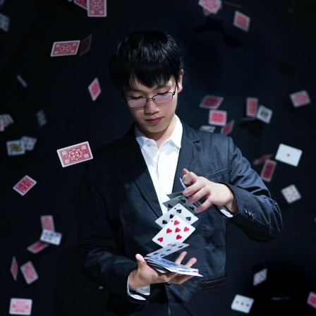 Ein junger Zauberer hält ein Kartenspiel in der Hand, um ihn herum fliegen einzelne Karten.