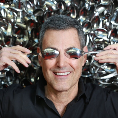 Uri Geller hält sich die Augen mit Löffeln zu