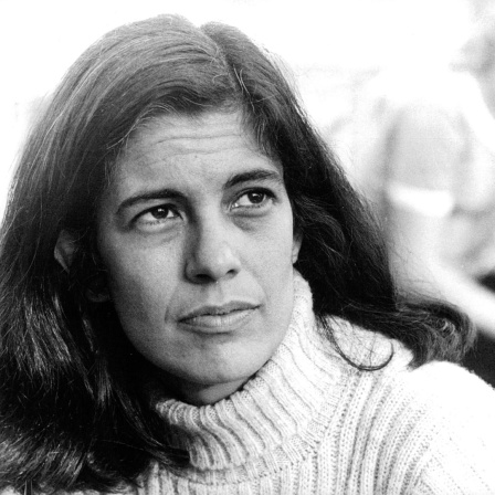 Schwarzweißporträt von Susan Sontag, die mit ernster Miene ins Off des Bildes blickt.