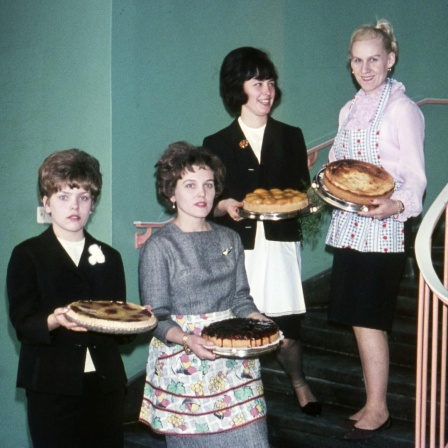 Vier Hausfrauen mit frisch gebackenem Kuchen stehen auf einer Treppe, ca. 1960.