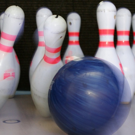 Ein blauer Ball wirft rot-weiße Kegel um.