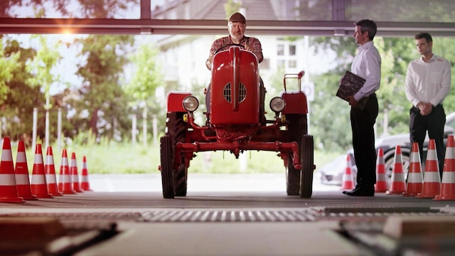 Ein Mann sitzt auf einem roten Traktor.