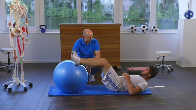 Dr. Helge Riepenhof betreut einen Patienten, der Übungen auf einer Fitnessmatte macht.