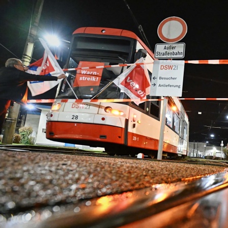 Straßenbahnen mit Verdi-Plakaten und -Flaggen stehen vor einem Depot der Dortmunder Verkehrsbetriebe DSW21. 