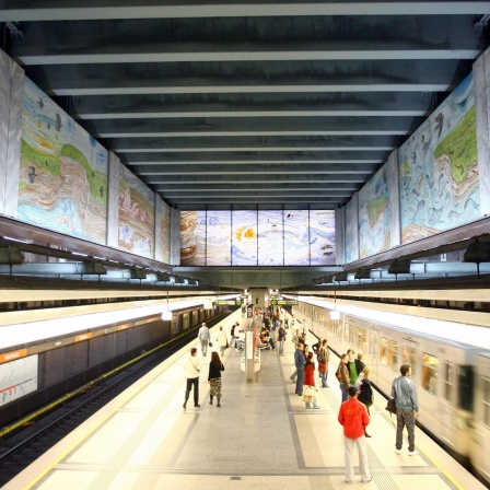 Einfahrender Zug in der U-Bahnstation Volkstheater in Wien. Am oberen Teil des Bildes sind die Wandgemälde ich der Station zu sehen.