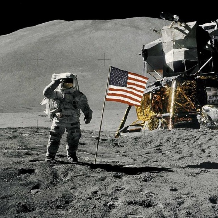 Bei Apollo 17 (im Dezember 1972) waren zum letzten Mal Menschen auf dem Mond. Auf dem Foto sieht man einen Astronauten, eine US-Flagge und ein Mondfahrzeug.