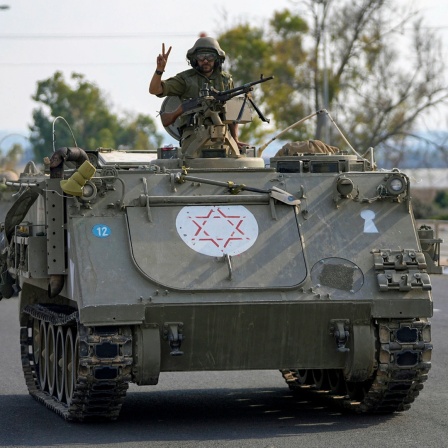 Ein israelischer Soldat zeigt das Victory-Zeichen von einem gepanzerten Mannschaftstransportwagen aus, der sich im Süden Israels auf die Grenze zum Gazastreifen zubewegt