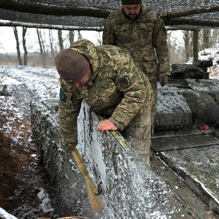 Ukrainische Soldaten beseitigen Schnee und Eis von einem Panzer (27.11.2023)