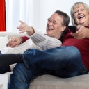 Armin Laschet und Hannelore Kraft liegen Arm in Arm auf einer Couch, Kraft hält eine Fernbedienung