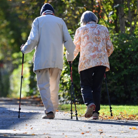 Altes Rentner-Ehepaar geht mit Nordic Walking Stoecken spazieren. 