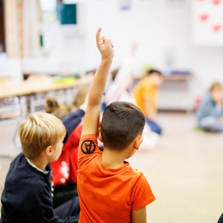 Schüler einer zweiten Klasse einer Grundschule im Stadtteil Neuperlach in München sitzen während des Unterrichts in einem Kreis auf dem Boden des Klassenzimmers zusammen und melden sich.