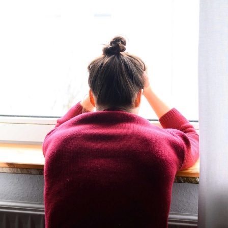 Symbolbild Einsamkeit: Eine Frau sitzt am Fenster und schaut hinaus.