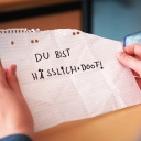 Ein Schüler liest einen Zettel auf dem steht "Du bist hässlich und doof"
