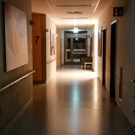 Ein Krankenhausgang in der Nacht, das Endes des Gangs ist beleuchtet.