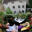Eine Dame liegt auf ihrem Balkon auf einem Liegenstuhl und liest die Zeitung