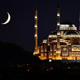 Blick auf die Mondsichel hinter einer Moschee.