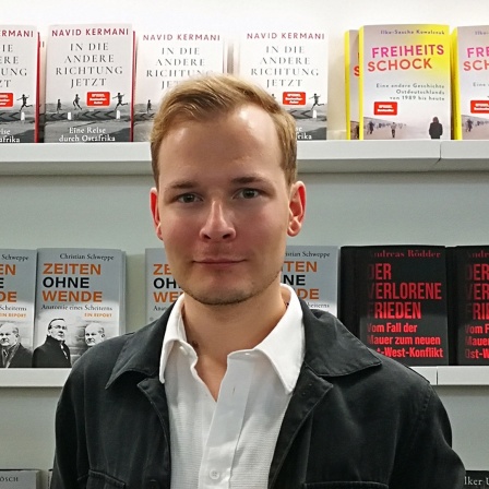 Der Buchautor Christian Schweppe steht in einer Buchhandlung.