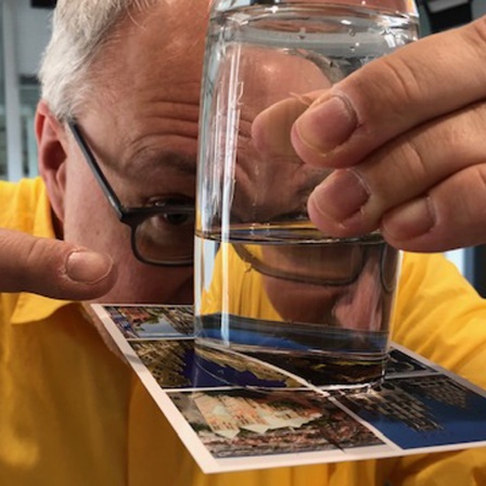 Joachim Hecker dreht ein Glas mit einer Postkarte um