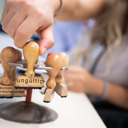 Eine Frau nimmt im Ausbildungsbürgeramt einen Stempel mit der Aufschrift «ungültig» aus einem Stempelhalter.