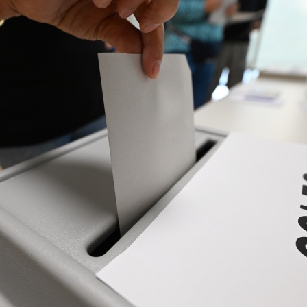 Ein Wahlzettel wird in eine Wahlurne geworfen