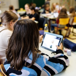 Schülerinnen einer sechsten Klasse arbeiten in einem Klassenraum während einer Unterrichtsstunde an ihren Tablets.