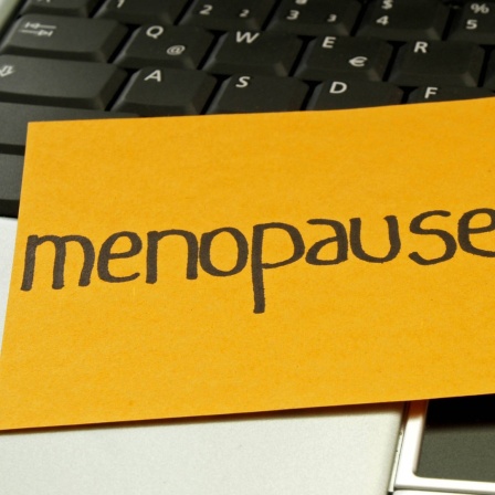 Ein Notizzettel mit der Aufschrift "Menopause" liegt auf einem Laptop