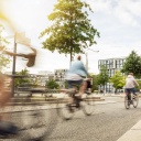 Straßenszene in einer Stadt mit auf einem breiten Fahrradweg fahrenden Fahrradfahrern.